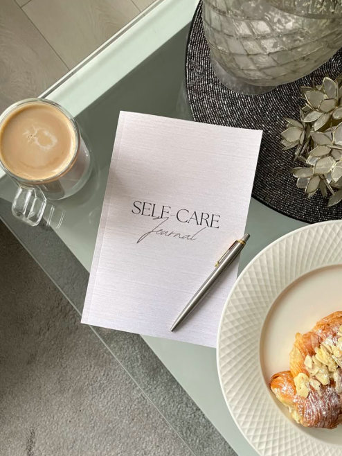 Rora Lane journal and planner on a glass desk with coffe and a croissant